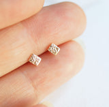 tiny gold squares in fingers for size reference