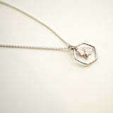 Silver bee necklace with a hexagonal pendant.